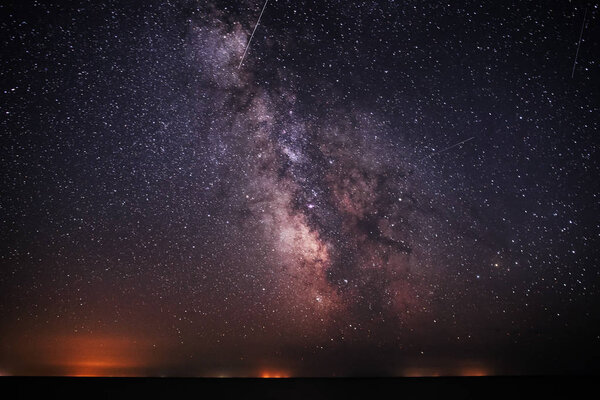 Фон яркого ночного звездного неба с Млечным Путем на нем и светом над водой
.