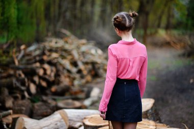 Kesilen ağaç gövdeleri ormandaki yığını üzerinde oturan güzel genç kadın.