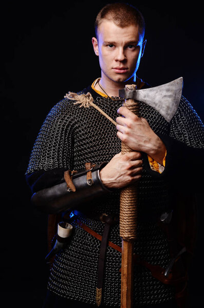 Male medieval warrior in armour and chain mail, viking with battle ax in hands .