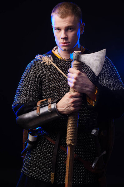 Male medieval warrior in armour and chain mail, viking with battle ax in hands .