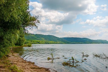 güzel göl manzara dağlar, yeşil ormanlar, aydınlık ve güneşli gökyüzü bulutlu.