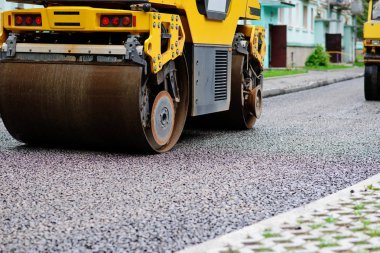Asfalt silindirinin arka planında sıcak asfalta basın. Yol tamir makinesi.