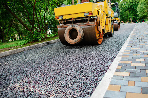 Carrying out repair works: asphalt roller stacking and pressing hot lay of asphalt. Machine repairing road.