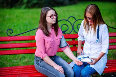 bakan doktor veya Hemşire Genç hastaya açık havada, bir bankta oturan alarak tutun konuşma