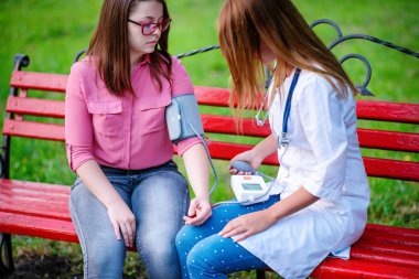 bakan doktor veya Hemşire Genç hastaya açık havada, bir bankta oturan alarak tutun konuşma