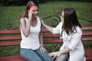 bakan doktor veya Hemşire Genç hastaya açık havada alarak, hasta baş ağrısı hakkında endişeleniyor