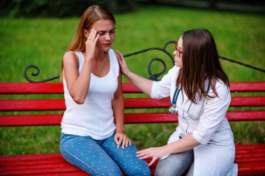 bakan doktor veya Hemşire Genç hastaya açık havada alarak, hasta baş ağrısı hakkında endişeleniyor