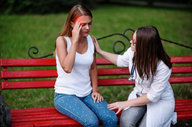 bakan doktor veya Hemşire Genç hastaya açık havada alarak, hasta baş ağrısı hakkında endişeleniyor