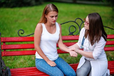 bakan doktor veya Hemşire Genç hastaya açık havada, bir bankta oturan alarak tutun konuşma