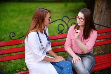 bakan doktor veya Hemşire Genç hastaya açık havada, bir bankta oturan alarak tutun konuşma