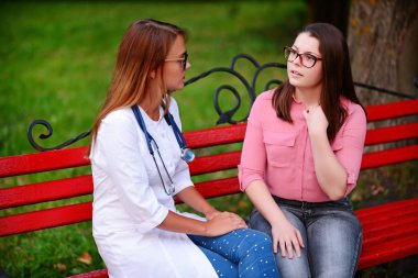 bakan doktor veya Hemşire Genç hastaya açık havada, bir bankta oturan alarak tutun konuşma