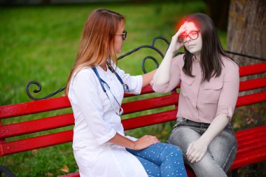 bakan doktor veya Hemşire Genç hastaya açık havada alarak, hasta baş ağrısı hakkında endişeleniyor