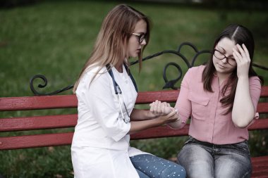 bakan doktor veya Hemşire Genç hastaya açık havada alarak, hasta baş ağrısı hakkında endişeleniyor