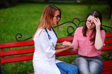 bakan doktor veya Hemşire Genç hastaya açık havada alarak, hasta baş ağrısı hakkında endişeleniyor