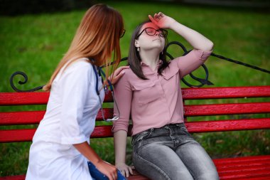 bakan doktor veya Hemşire Genç hastaya açık havada alarak, hasta baş ağrısı hakkında endişeleniyor