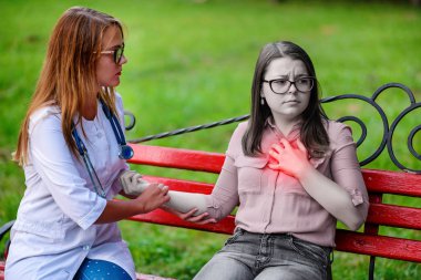 bakan doktor veya Hemşire Genç hastaya açık havada, bir bankta oturan alarak tutun konuşma.