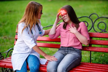 bakan doktor veya Hemşire Genç hastaya açık havada alarak, hasta baş ağrısı hakkında endişeleniyor.