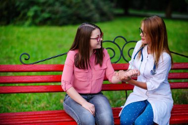 bakan doktor veya Hemşire Genç hastaya açık havada, bir bankta oturan alarak tutun konuşma.