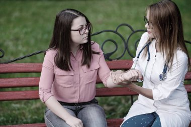 bakan doktor veya Hemşire Genç hastaya açık havada, oturan bir tezgah ve darbe testi alarak.