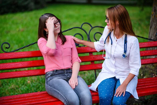 bakan doktor veya Hemşire Genç hastaya açık havada alarak, hasta baş ağrısı hakkında endişeleniyor