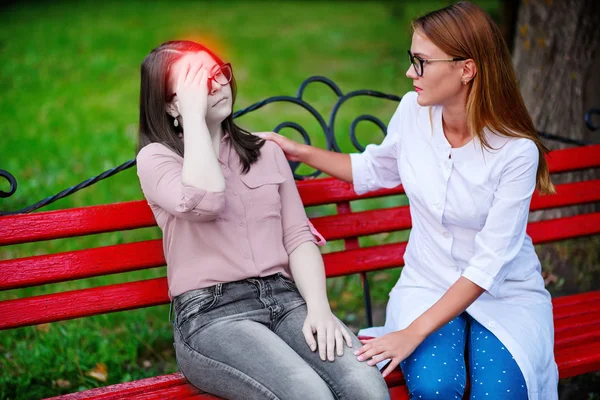 bakan doktor veya Hemşire Genç hastaya açık havada alarak, hasta baş ağrısı hakkında endişeleniyor