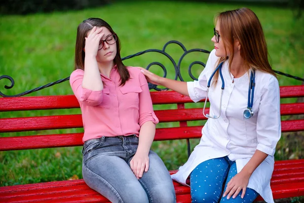 bakan doktor veya Hemşire Genç hastaya açık havada alarak, hasta baş ağrısı hakkında endişeleniyor