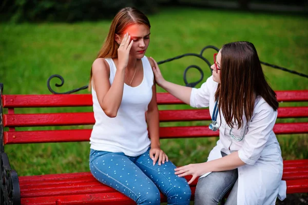 bakan doktor veya Hemşire Genç hastaya açık havada alarak, hasta baş ağrısı hakkında endişeleniyor