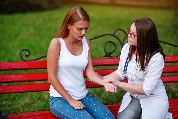 bakan doktor veya Hemşire Genç hastaya açık havada, bir bankta oturan alarak tutun konuşma
