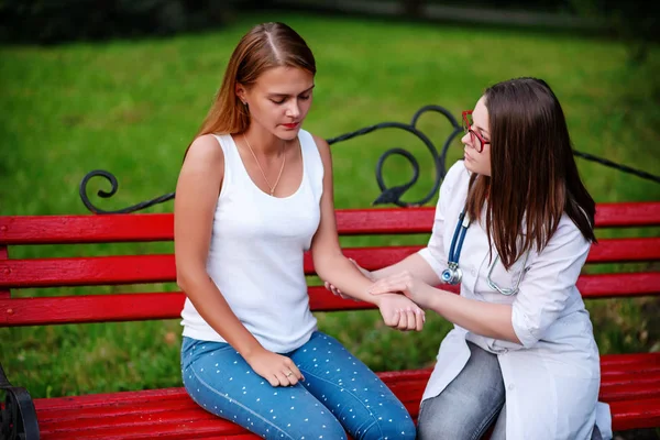 bakan doktor veya Hemşire Genç hastaya açık havada, bir bankta oturan alarak tutun konuşma