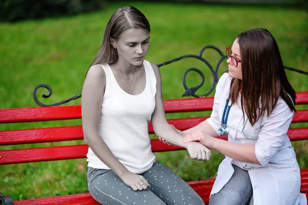 bakan doktor veya Hemşire Genç hastaya açık havada, bir bankta oturan alarak tutun konuşma