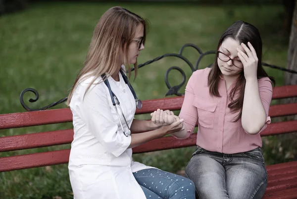 bakan doktor veya Hemşire Genç hastaya açık havada alarak, hasta baş ağrısı hakkında endişeleniyor