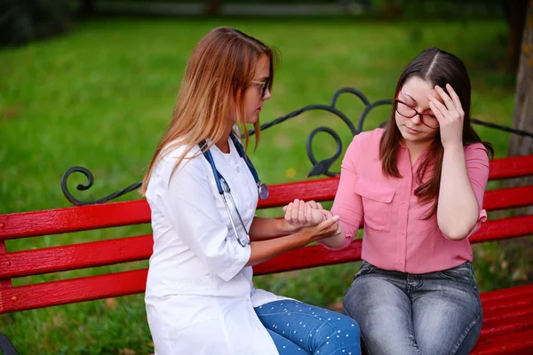 bakan doktor veya Hemşire Genç hastaya açık havada alarak, hasta baş ağrısı hakkında endişeleniyor