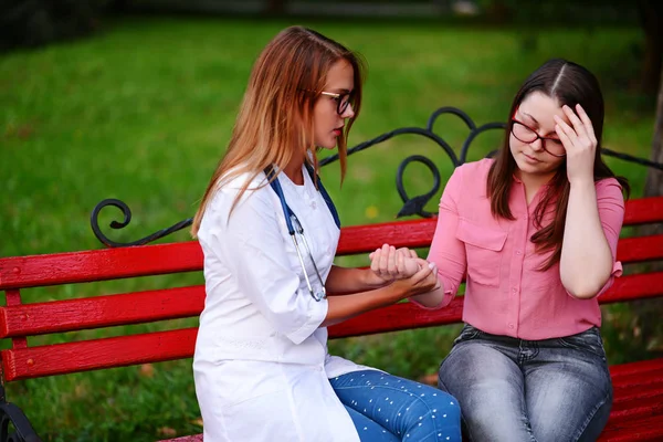 bakan doktor veya Hemşire Genç hastaya açık havada alarak, hasta baş ağrısı hakkında endişeleniyor