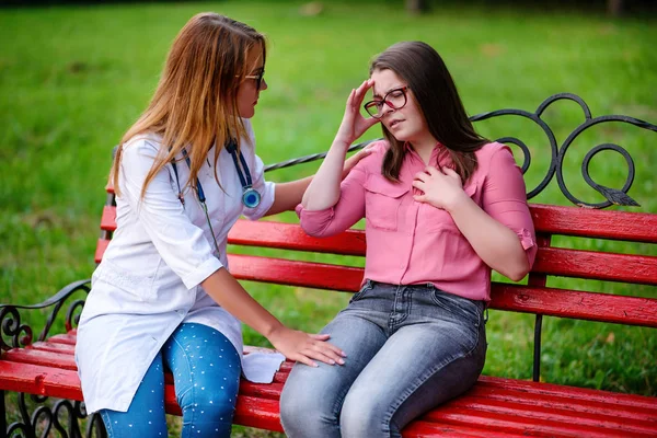 bakan doktor veya Hemşire Genç hastaya açık havada alarak, hasta baş ağrısı hakkında endişeleniyor
