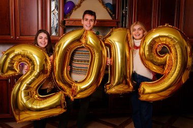 Yeni 2019 yıl geliyor. Gençlerin grup altın taşıyan neşeli numaraları renkli ve partide iyi eğlenceler.