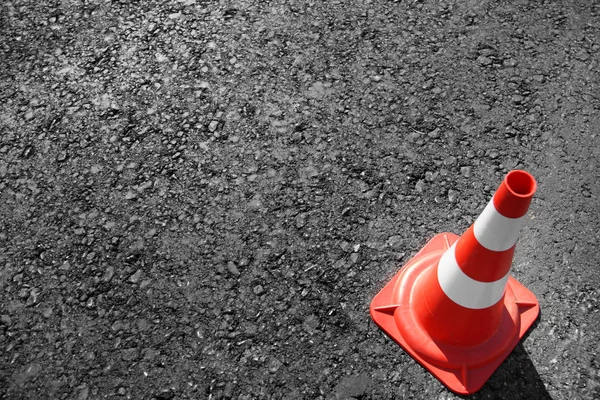 traffic cone, with white and orange stripes on gray asphalt, copy space.