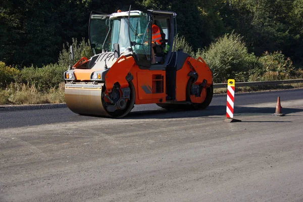 Carrying out repair works: asphalt roller stacking and pressing hot lay of asphalt. Machine repairing road.