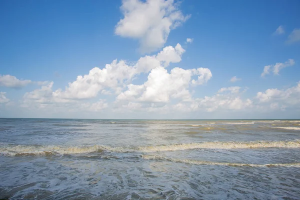 Güçlü dalgalar ve çamurlu suyla dolu bir günde deniz, mavi gökyüzü arka planı tatilde o kadar da güzel değildir..
