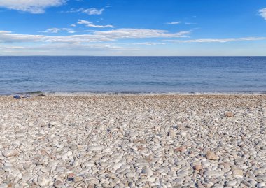 Bulutlu mavi gökyüzü ile çakıl taş Plajı