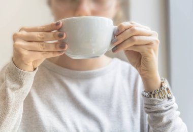 Güzel cafe latte beyaz fincan kafeteryasında bir kız elinde