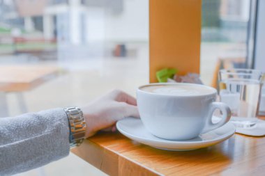 Parlak gün cafe latte kafeteryasında büyük beyaz bardak tutan kız