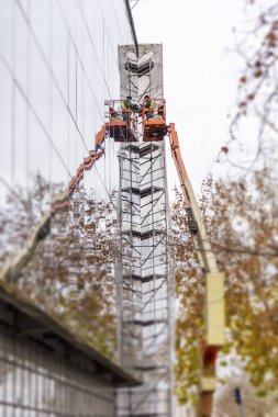 Cam pencere binanın üst kısmında bir vinç, platform üzerinde çalışan adam kaldırdı