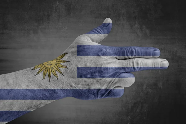 Uruguay flag painted on male hand like a gun