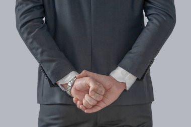 İş adamı ellerini arkasında tutuyor.