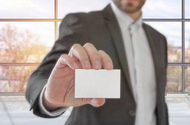 Ofiste elinde beyaz kağıt tutan bir işadamı var.