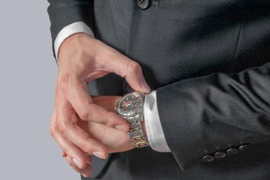 İş adamı saatine bakıyor, saati izliyor.