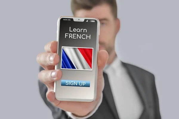 Online concept learn French language with a person showing e-learning app on mobile phone with the flag of France isolated