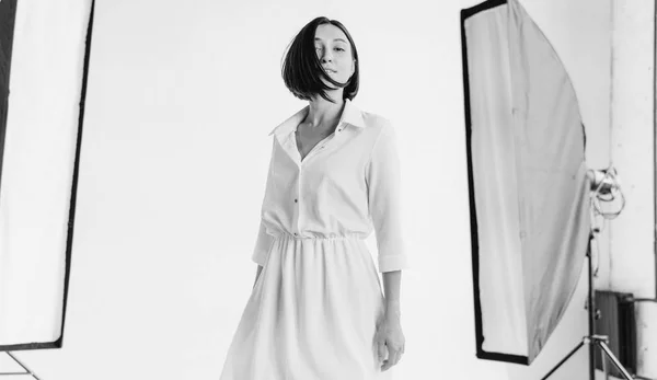 Elegante chica caucásica en vestido blanco mirando a la cámara en el estudio. Estilo de grano de película —  Fotos de Stock