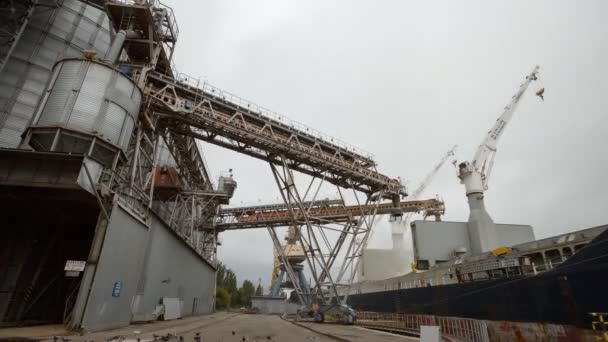 Calendário do terminal de grãos no porto no dia nublado. Transbordo a granel de cereais para navios que carregam culturas de cereais em navios a granel a partir de grandes elevadores no cais. Transporte de produtos agrícolas . — Vídeo de Stock