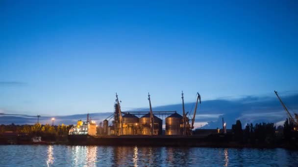 Timelapse terminal de grano grande en el puerto marítimo por la noche. Transbordo de cereales a granel al buque por la noche. Carga de cultivos de grano en el barco desde grandes ascensores en el amarradero. Transporte de productos agrícolas . — Vídeos de Stock